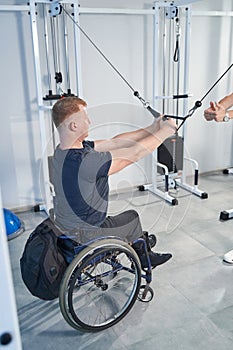 Man with disability exercises with resistance band in therapy room