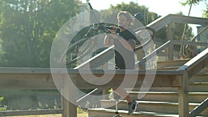 Man with disability holding bike in hands and descending stairs