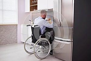 Man With Disability Sitting In Wheel Chair Preparing Food