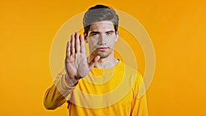 Man disapproving with NO hand sign gesture. Denying, rejecting, disagree, portrait of guy or student on yellow