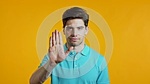 Man disapproving with NO hand sign gesture. Denying, rejecting, disagree, portrait of guy or student on yellow