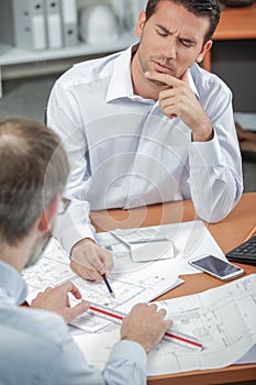 man discussing blueprints frowning during meeting