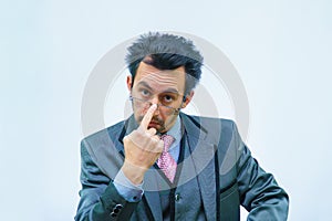 A man with disheveled hair in a business suit adjusts his glasses