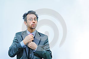 A man with disheveled hair in a business suit straightens his tie.