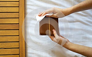 Man disinfecting his wallet with a disinfecting wipe.