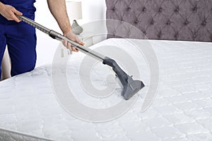Man disinfecting mattress with vacuum cleaner