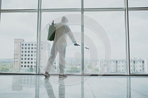 Man disinfector worker cleaning office space and window before work on corona virus pandamia