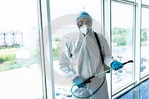 Man disinfector worker cleaning office space and window before work on corona virus pandamia