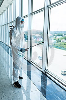 Man disinfector worker cleaning office space and window before work on corona virus pandamia