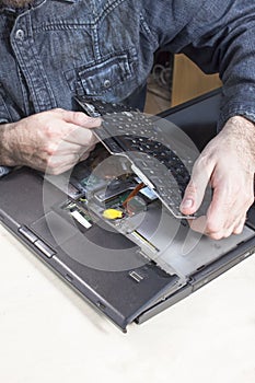 The man dismantles the laptop casing in the electronic equipment service.