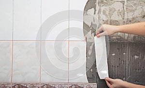 A man dismantles old tiles from the wall in the kitchen. Repair in the apartment, close-up