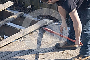 Man Dismantling an Old Wooden Deck with a Red Crowbar  1