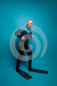 Man in diver wear holding thumb up on blue background