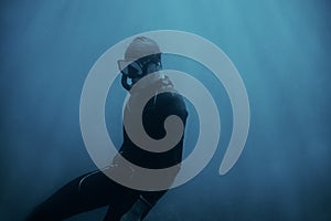 Man diver in wetsuit swimming underwater.