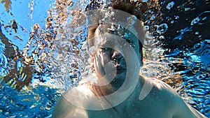 a man dives into the pool with a camera in his hands. shooting under water.