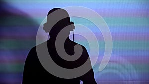 Man DJ silhouette on wall, performing for party, dancing to music, back view