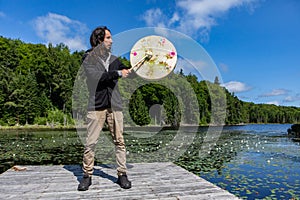 Man on dock with sacred drum and stick