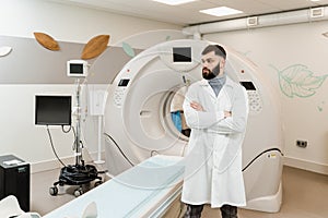 Man doctor in CT scan computed tomography room in medical clinic. Handsome bearded doctor in medical robe with computed