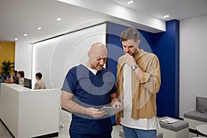Man doctor discussing with patient results of routine checkup in corridor