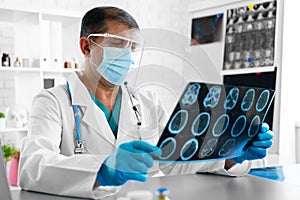 Man doctor examining head mri while sitting at the table in hospital