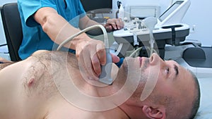 Man doctor examining patient thyroid gland using ultrasound scanner, side view.