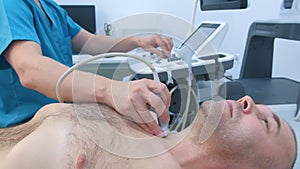 Man doctor examining patient thyroid gland using ultrasound scanner, side view.