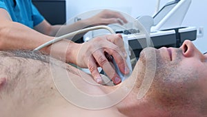 Man doctor examining patient thyroid gland using ultrasound scanner, side view.