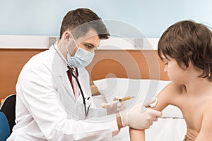 Man doctor in medical uniform making injection to child patient