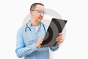 Man doctor pointing with finger at blank paper on clipboard, white background.