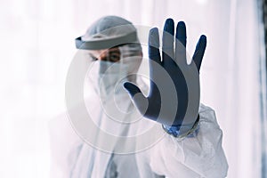 Man doctor or scientist waring protective suit and face mask , STOP, hand gesture photo