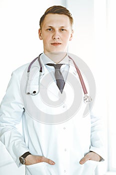 Man-doctor standing straight in sunny clinic. Medicine concept