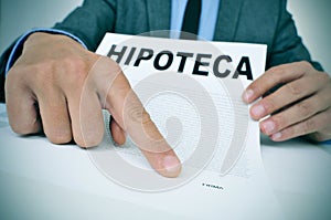 Man with a document with the word hipoteca, mortgage loan contra