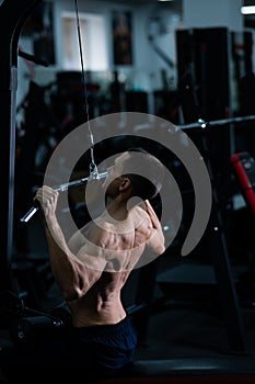 A man does a chest pulldown in the gym.