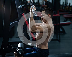 A man does a chest pulldown in the gym.