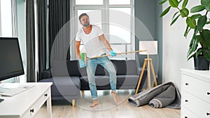 Man does the cleaning and imagines himself a rock star, plays the broom like a guitar.