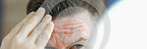 Man does gel hair styling in front of mirror.