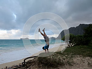 Man does handstand on grassy bluff on Waimanalo beach