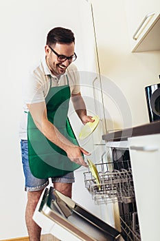 Man does housework in the kitchen, loads the dishes