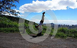 Man does Mayurasana or Peacock Pose on tree stump in the mountains of Oahu