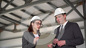 The man does not approve the project. Young man and woman in helmets with documents at a construction site. Bosses in