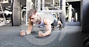 Man does plank pose to strengthen body muscles in gym