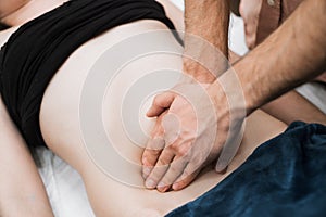 A man does a woman a massage of the abdomen, osteopathy