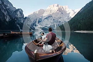 Man and dog in a boat on a mountain lake. Trip with a pet to Italy. Australian Shepherd Dog and its owner