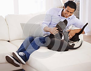 Man, dog and happiness with laptop on sofa for bonding, playing and face with remote work in home. Animal, person and