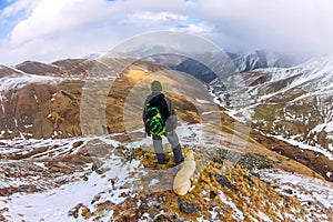 Man and dog labrador hike the cloudy mountains