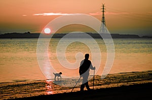 Man with dog nordic walking at the river beach