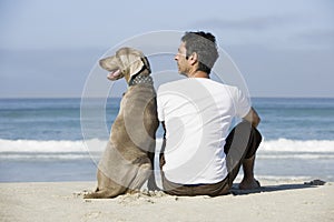 Man And Dog Sitting On Beach