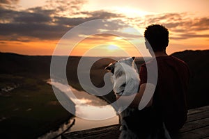 A man with a dog at sunset. walk with a pet. Australian Shepherd and owner in nature