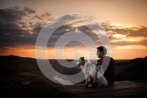 A man with a dog at sunset. walk with a pet. Australian Shepherd and owner in nature