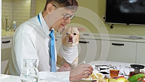 The man with the dog at the table is eating. Friendship of man and pet. Businessmen concept